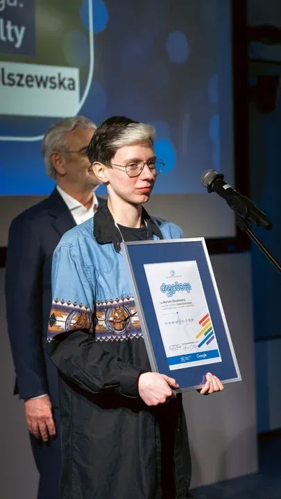 Laureat trzymający oprawiony dyplom konkursowy